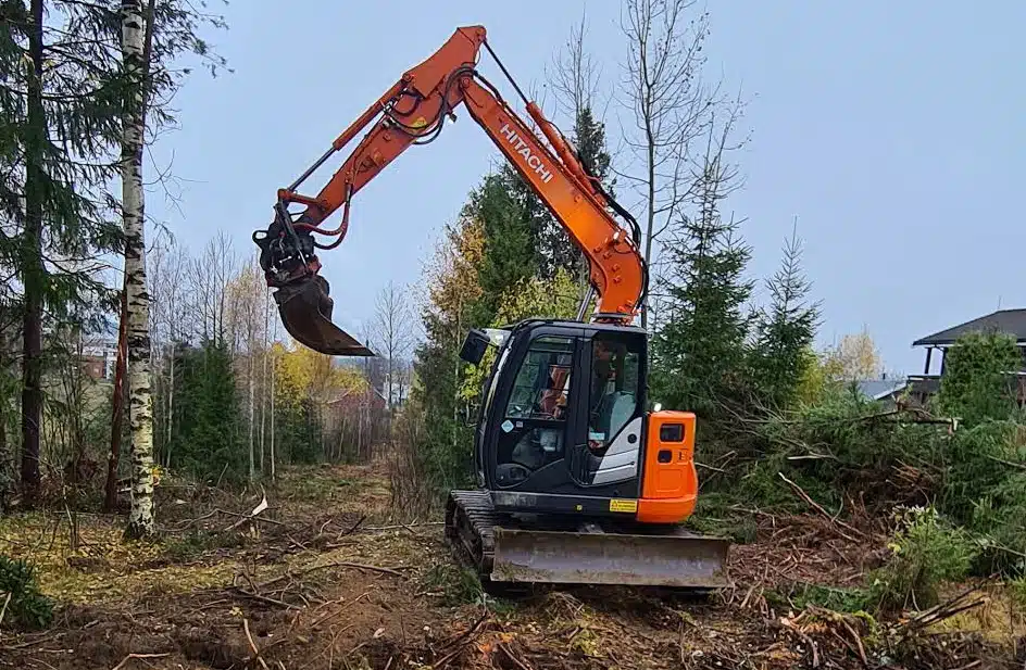 Gravemaskin som graver med trær rundt